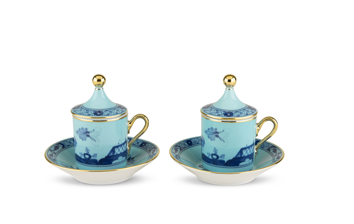 Two light blue Oriente Italiano Dinnerware Iris lidded cups and saucers by Ginori 1735, decorated with chinoiserie floral and architectural patterns and finished with gold-toned handles and finials.