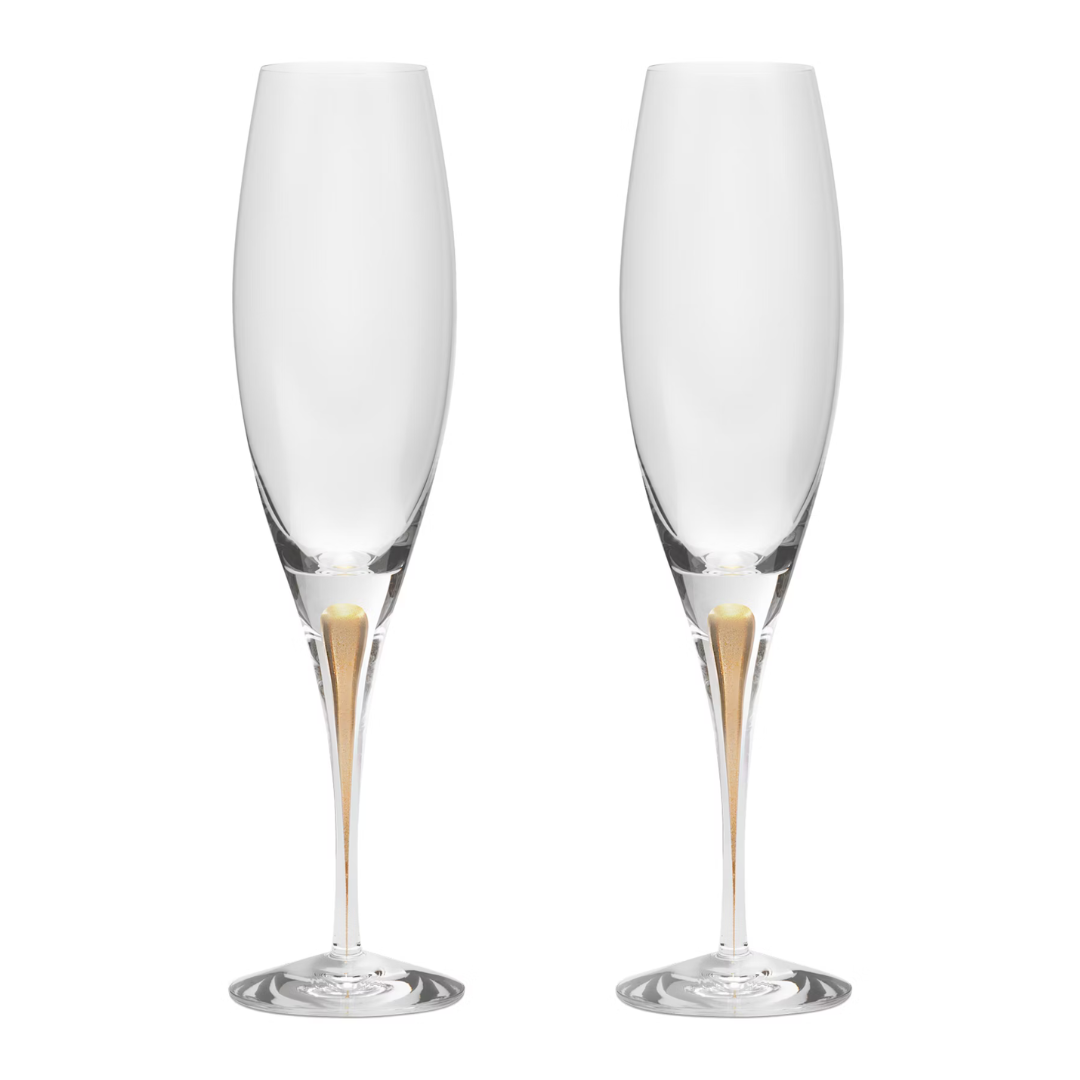 The Orrefors Kosta Boda Intermezzo Champagne Glass Gold Set of 2, designed by Erika Lagerbielke from mouth-blown glass, features long stems and a gold accent at the base, shown side by side on a white background.