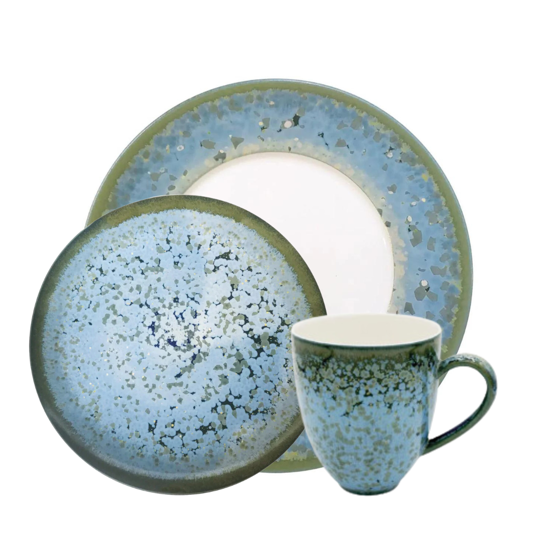 The Jaune De Chrome Nymphea Dinnerware set features Limoges porcelain with a blue speckled design and green edges, including a dinner plate, salad plate, and matching handled mug.