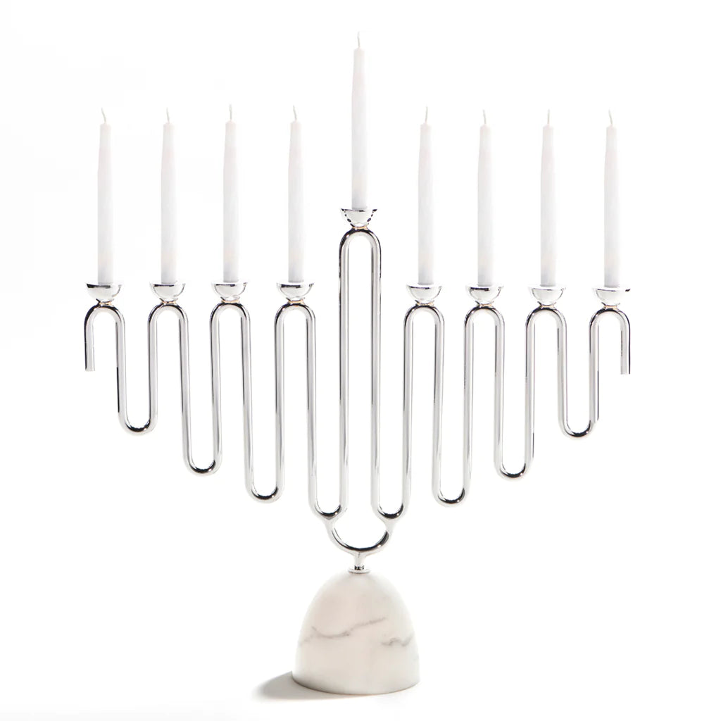 The Coluna Menorah Carrara Marble & Silver by Anna New York features a sleek geometric silver design that holds nine white candles, set atop a refined base of Italian Carrara marble against a plain white background.