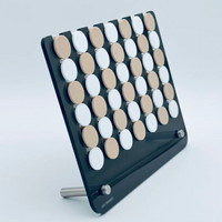The Luxe Dominoes Connect Four JUMBO EDITION El Cuatro—LAST ONE! features a black angled stand with a grid of beige and white buttons, giving a minimalist family game feel against a plain background.