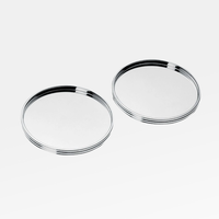 The Christofle K+T Two Silver-Plated Coasters are shown side by side on a white background, each featuring a raised edge and a smooth, reflective finish.