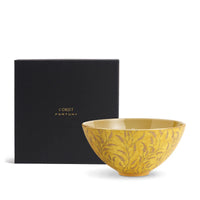 The Fortuny Orfeo Serving Bowl Yellow - Medium by L'Objet features an intricate leaf pattern and gold detailing and is displayed in front of a black box labeled "L'OBJET FORTUNY" in gold letters.
