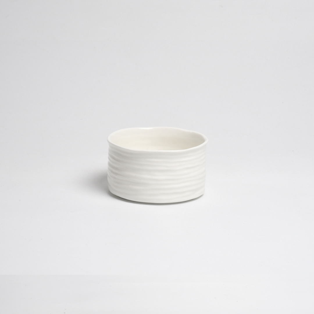 The PAMPA BAY Le Blanc Bowl features a textured, wavy white porcelain design and sits stylishly on any surface; it's both oven safe and dishwasher safe for versatile use.