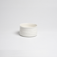 The PAMPA BAY Le Blanc Bowl features a textured, wavy white porcelain design and sits stylishly on any surface; it's both oven safe and dishwasher safe for versatile use.