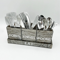 The Eye Candy Let's Eat Silverware Caddy in Grey Marble features three labeled containers for forks, knives, and spoons with silver utensils, set in a matching acrylic "EAT" tray—an elegant choice for any modern table.