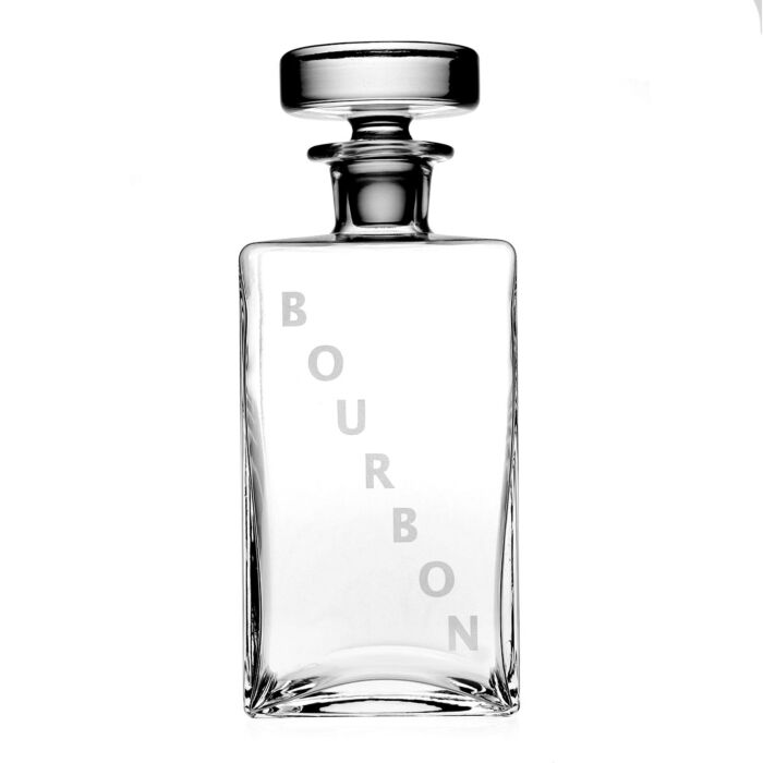 The Lillian Decanter Bourbon by William Yeoward is a clear, handmade crystal glass decanter with a round stopper and "BOURBON" printed vertically in large, light letters. The empty bottle is shown against a white background.