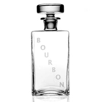 The William Yeoward Lillian Decanter Bourbon is a clear, rectangular crystal glass decanter with a round stopper and "BOURBON" in large vertical letters on the front, shown empty against a white background.