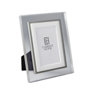 The Prisma Frame Lip - Grey by Bella Moulding is a clear acrylic photo frame with a silver inner border, designed to display photos at an angle. Crafted from archival materials, it beautifully preserves your memories.