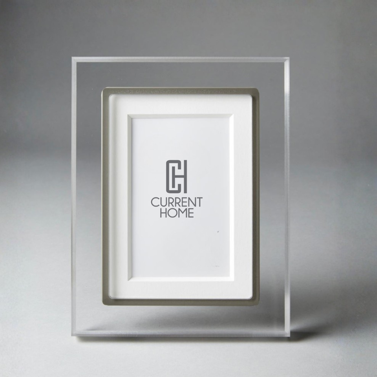 The Prisma Frame Lip - Grey by Bella Moulding is a clear acrylic photo frame with a silver inset and white mat, crafted from archival materials. The frame features the Current Home logo on the white mat.