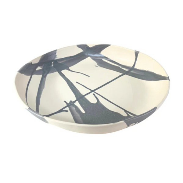 The Low Handmade Serving Bowls by Alex Marshall Studios are shallow ceramic bowls with a cream base and abstract dark blue and black brushstroke patterns inside and out—an elegant example of handcrafted pottery.