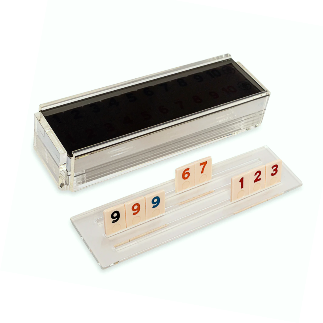 The Luxe Dominoes Rummy Acrylic Game Set features a clear acrylic box with numbered tiles in red, blue, and black plus two trays—an elegant gift for game lovers.