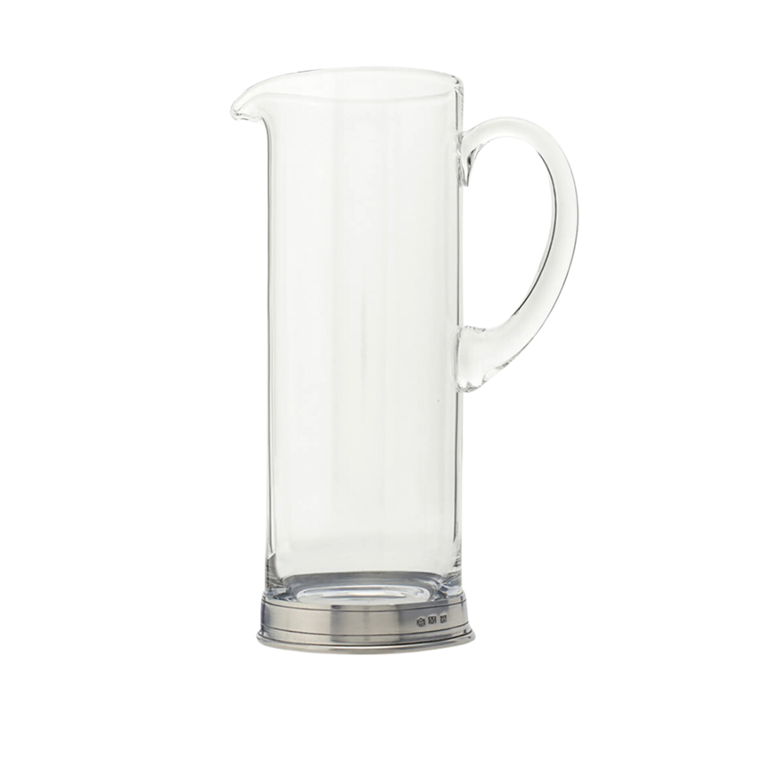 The MATCH Martini Crystal Pitcher by MATCH features a clear glass design with a curved handle, pouring spout, and a shiny handmade pewter base crafted by Italian artisans, shown against a white background.