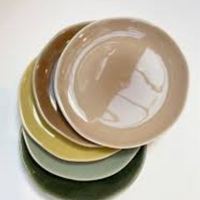 Five ceramic plates with crackled glazes in beige, green, and yellow are unevenly stacked on a white background, viewed from above. Shown: Maguelone Dinnerware Tamaris by Jars - Rosenthal.