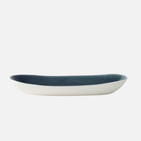The Maguelone Outremer Dark Blue by Jars - Rosenthal is a shallow, oval ceramic dish with a white exterior and deep blue interior, part of our Mediterranean-inspired collection, displayed against a plain white background.