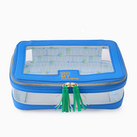 Introducing the Mahjong Tile Storage Bag by Oh My Mahjong—a blue Mahjong organizer featuring clear plastic sides and top, accented with gold zippers and green tassels. The front displays “OH MY MAHJONG” in gold lettering. Inside, you’ll find a chic blue-and-white striped lining, making it ideal for stylish and organized storage of your mahjong tiles.