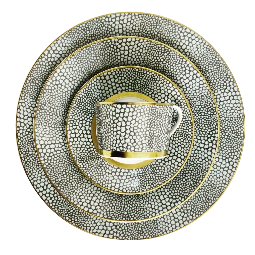 The Makassar Gold Dinnerware set by Royal Limoges features a cup, saucer, and three plates with a black and white pebble pattern and gold trim, expertly handmade in France from fine Limoges porcelain.