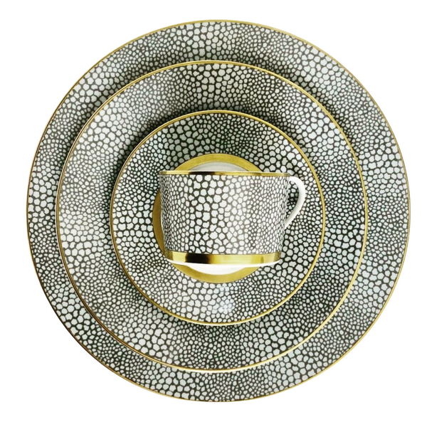 The Makassar Gold Dinnerware set by Royal Limoges features a cup, saucer, and three plates with a black and white pebble pattern and gold trim, expertly handmade in France from fine Limoges porcelain.