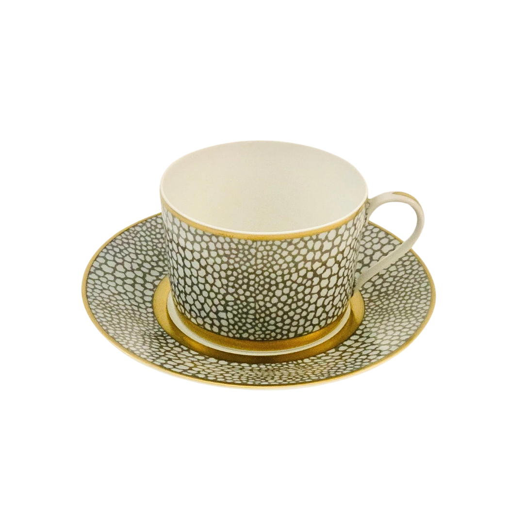 The Makassar Gold Dinnerware teacup and saucer by Royal Limoges is handmade in France from Limoges porcelain, featuring a gray and white pebble-like pattern with elegant gold accents and gold filet on a white background.