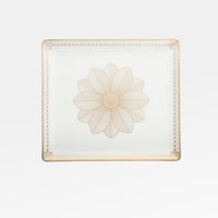 The Malmaison Porcelain Catchall Tray by Christofle is a square white Limoges porcelain piece with gold geometric accents, a detailed gold flower at the center, and Malmaison Impériale gold edging on the corners.