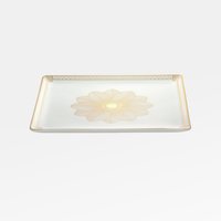 The Christofle Malmaison Porcelain Catchall Tray features an intricate gold floral centerpiece and a geometric gold rim, showcasing elegant Malmaison Impériale style against a classic white background.