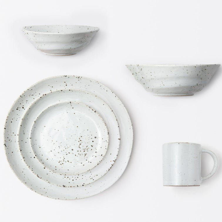 A Blue Pheasant Marcus Dinnerware Set in White Salt Glaze, featuring two bowls, two differently sized plates, and a mug, is arranged neatly on a white background.