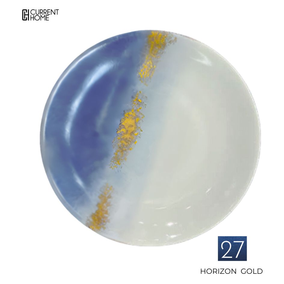 The Marie Daâge Horizon Gold Dinnerware features a round porcelain plate with a hand-painted blue and white gradient, accented by a gold streak. "Marie Daâge" logo in the top left; "27 Horizon Gold" in the bottom right.