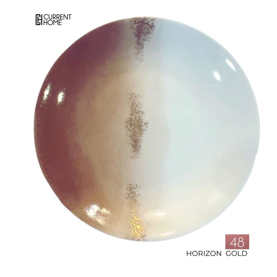 The Marie Daâge Horizon Gold Dinnerware features a round porcelain plate with a vertical gold, brown, and white gradient design and hand-painted details. The Marie Daâge logo appears in the top left. Made in France.