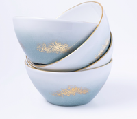 Three stacked Marie Daâge Horizon Gold Dinnerware bowls by Marie Daâge, with a blue and white gradient, gold textured accents, and slim gold rims, elegantly displayed against a plain white background.