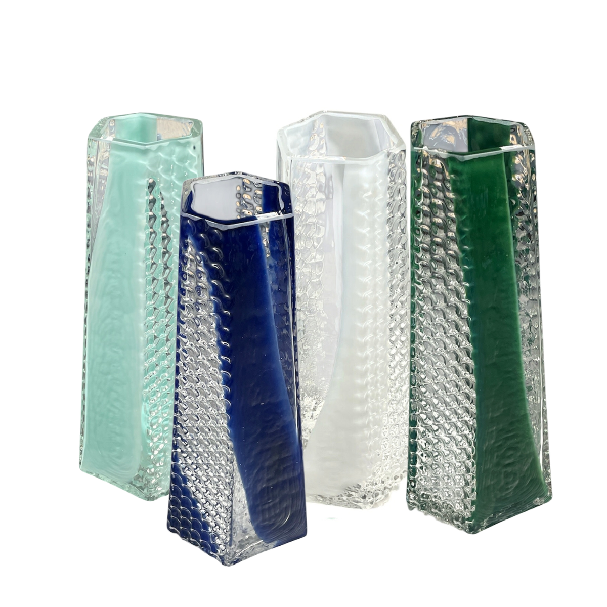 Five BB Faceted Mini Vases by Matt Kolbrener in light blue, dark blue, clear, green, and light green stand together on a white background. Each handblown glass vase features a geometric, rectangular shape inspired by industrial design.