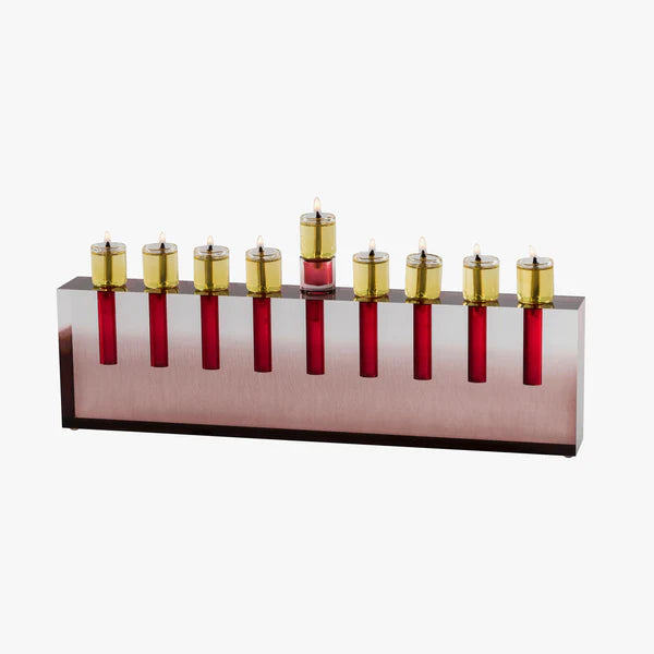 The Apeloig Modern Acrylic Oil Menorah features a rectangular silver base with nine red glass candle holders and gold-colored oil cups, each lit with a small flame, offering modern customization for your celebration.