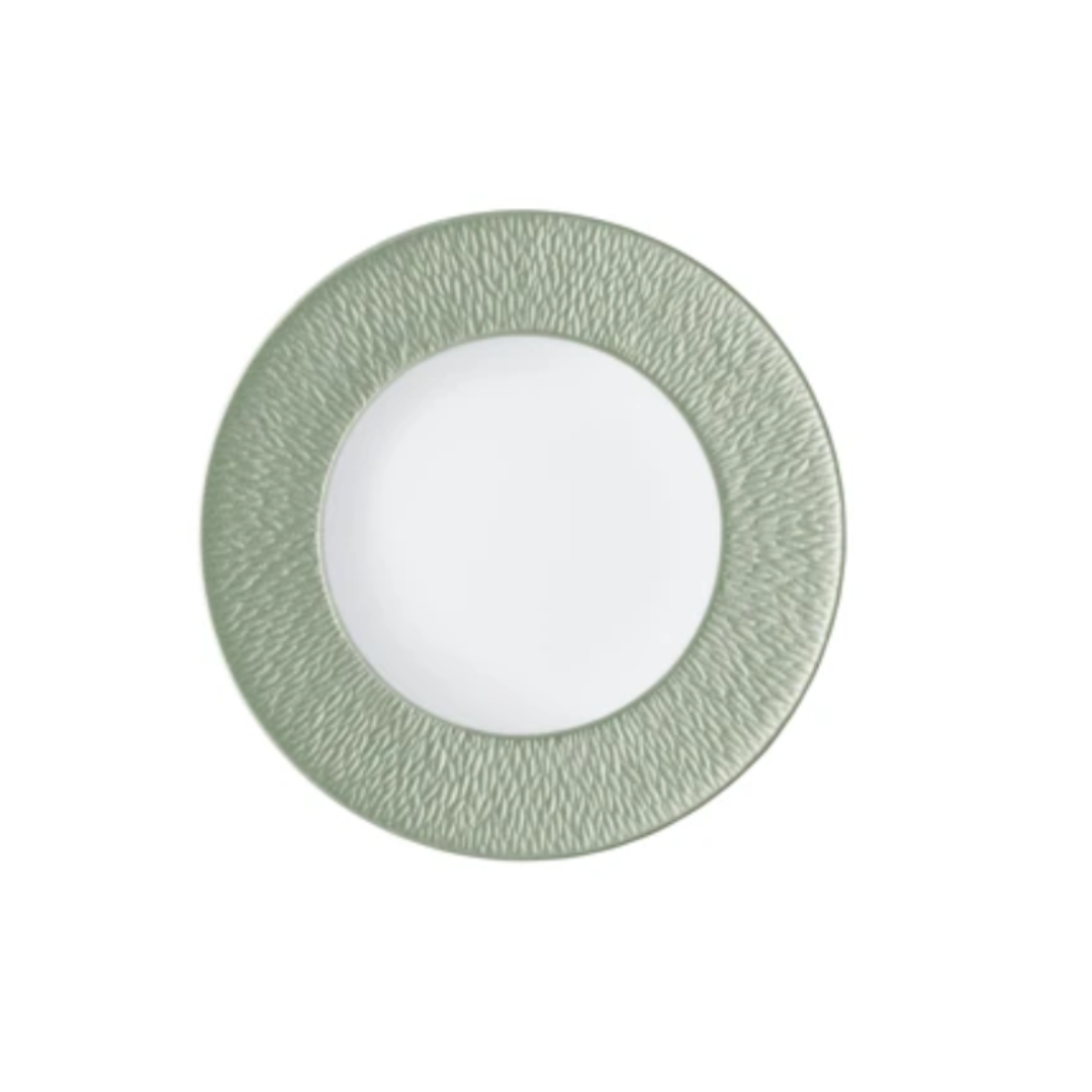 A round Limoges porcelain plate from Raynaud’s Mineral Irise Dinnerware - Celadon, featuring a textured light green rim and smooth white center, is displayed against a plain white background.