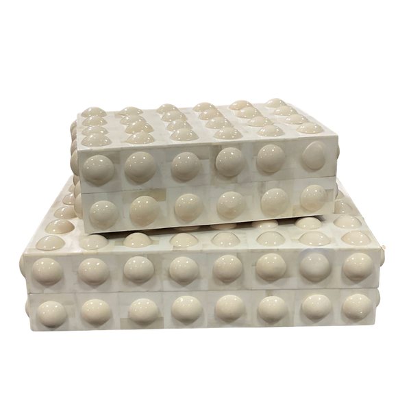The Moondrops Box by A Sanoma Inc features two stacked white rectangular boxes with a grid of raised round bumps, creating a bold geometric design reminiscent of oversized building blocks—a striking accessory for any modern space.