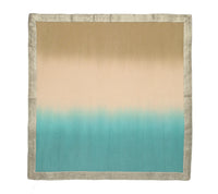 The Kim Seybert Dip Dye Napkins - Cool Tones - Set of 4 features a beige to cream and turquoise gradient, accented with a metallic foil border for elegance.