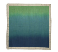 The Kim Seybert Dip Dye Napkins - Cool Tones (Set of 4) feature square linen with a beige border and a stylish gradient that transitions from green to blue to dark blue, creating a chic dip dye effect.