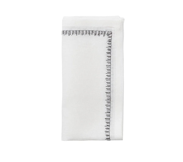The Kim Seybert Filament Napkin White & Gunmetal Set of 4 features neatly folded white linen napkins with an elegant gunmetal stitched border, displayed against a plain white background.