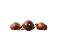 The Bois Napkin Ring Set of 4 by Kim Seybert features polished brown wooden spheres accented with small gold dots, arranged in a wave pattern for an elegant, hand-crafted look.