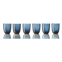 The Nason Moretti Idra Mixed Pattern Glass Set of 6 showcases blue glass tumblers, each with a unique texture, inspired by Murano artistry and arranged on a reflective surface with a white background.