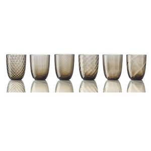 The Idra Mixed Pattern Glass Set of 6 by Nason Moretti features short, smoky-colored tumblers with unique textures and patterns, inspired by Murano glass and expertly crafted in Italy.