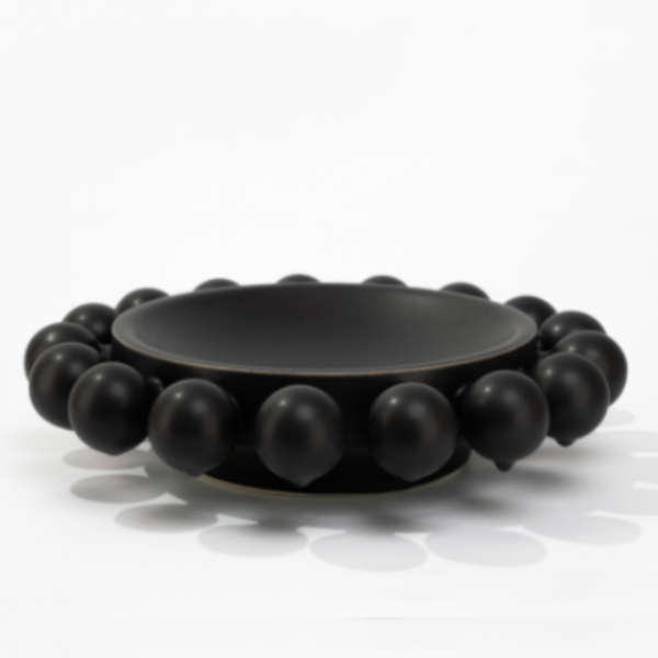 The KleinReid Nimbus Halo Bowl is a round, black porcelain piece from the Nimbus Collection, featuring large, evenly spaced spherical knobs encircling the rim, shown against a white background.