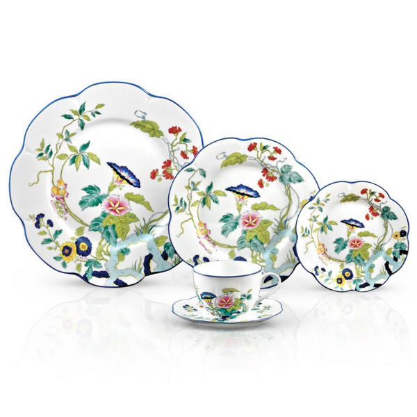 The Royal Limoges Nymphea Paradis Bleu set includes four plates and a teacup, each featuring colorful floral and bird motifs on white porcelain with scalloped blue-rimmed edges.