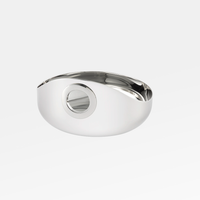 The Christofle Oh De Small Stainless Steel Bowl features a sleek oval shape with a circular cutout, reflecting light beautifully. This minimalist, multi-purpose bowl blends modern design and functionality, making it an elegant addition to any setting.