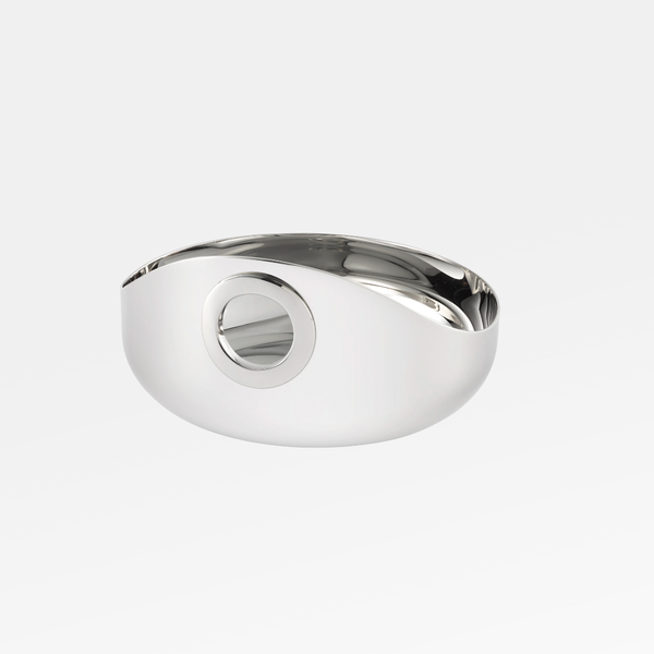 The Christofle Oh De Small Stainless Steel Bowl features a sleek oval shape with a circular cutout, reflecting light beautifully. This minimalist, multi-purpose bowl blends modern design and functionality, making it an elegant addition to any setting.