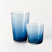 Two Gary Bodker “Everyday Glasses Midnight”—a tall and a short blue hand-blown tumbler—are placed side by side on a plain white background.