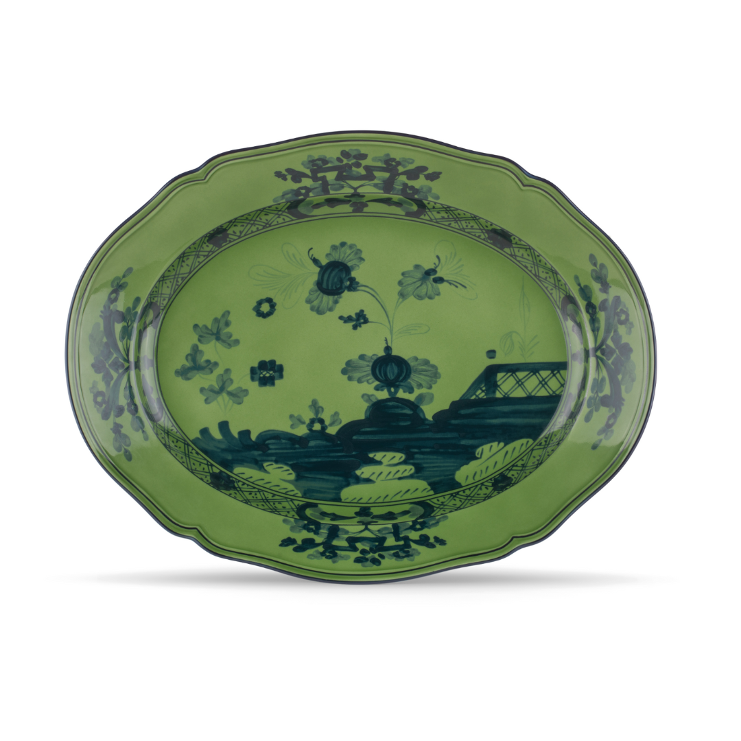 The Ginori 1735 Oriente Italiano Oval Platter—Large features green porcelain with scalloped edges, a dark blue floral and landscape center, and decorative motifs along the rim.