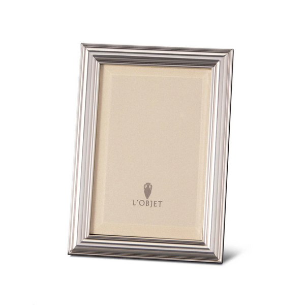 The Oscar Frame Platinum by L'Objet is a silver rectangular frame with a ridged border and sleek angular design, standing upright to display a blank insert featuring the L'Objet logo at the center.