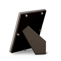 The Oscar Frame Platinum by L'Objet is shown from the back, highlighting its upright stand. Set against a white background, the luxury frame features a sleek, angular design crafted in dark platinum-finished material.