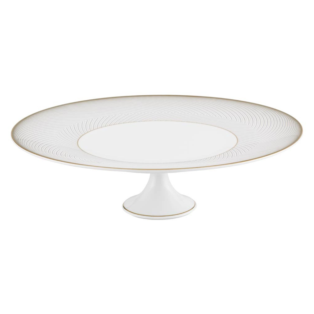 The Raynaud Oskar Dinnerware cake stand is crafted from white Limoges porcelain with a wide, flat top, short pedestal base, subtle gold rim accents, and a delicate geometric design near the edge.
