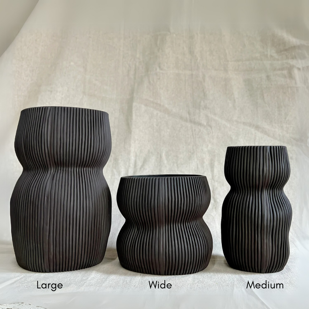Three black Curvy Oval Vases by CYM Warkov Ceramics, each with a ribbed, wavy texture in Large, Wide, and Medium sizes (left to right), are displayed on a light surface against a neutral background.