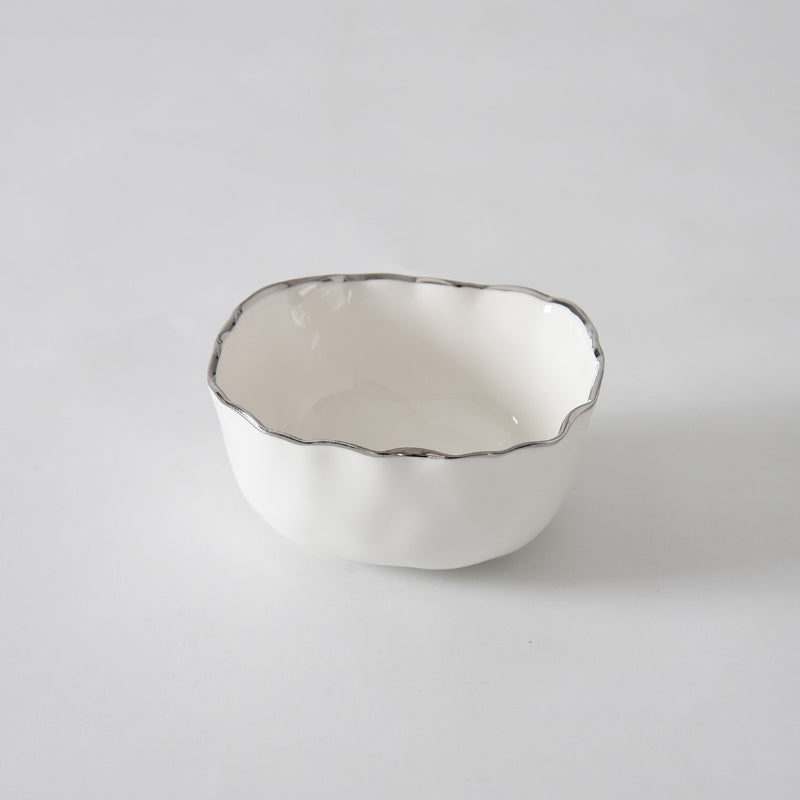 A small, white porcelain serving bowl with a wavy silver-edged rim, the PAMPA BAY Portofino Plata Bowl adds timeless elegance to your serveware collection as it sits beautifully on a plain white surface.